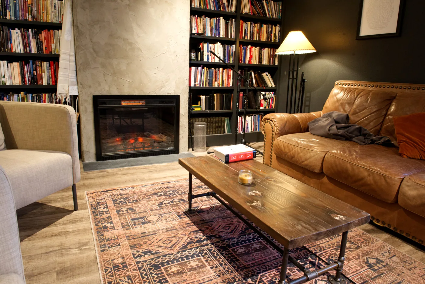 Community rental space in St. Johns, Portland: a lounge with a fireplace, leather sofa and bookshelves