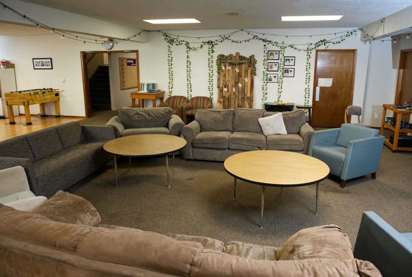 Meeting space for rent at St Johns Church: a large room with sofas, round tables and string lights
