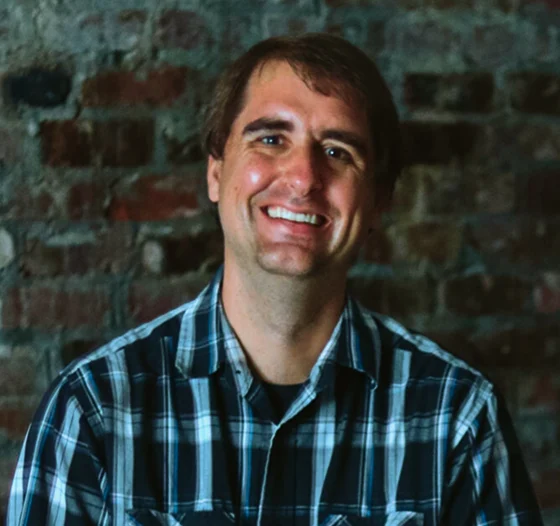 Pastor David smiling in front of a brick wall