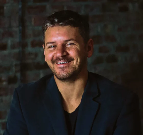 Pastor Josh smiling in front of a brick wall